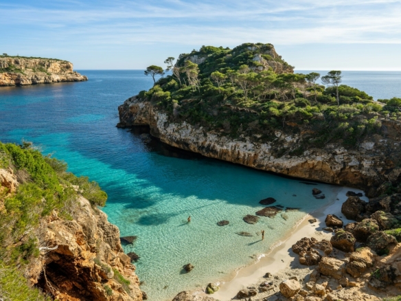 a beach with clear blue water next to a cliff