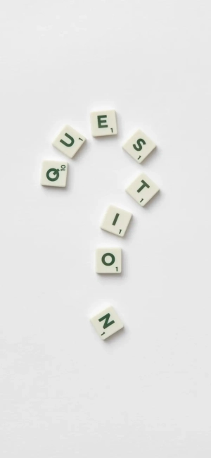 Artistic arrangement of letter tiles forming a question mark on a white background.